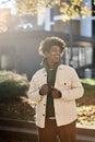 Cool happy young African American guy standing at big city sunny street. Royalty Free Stock Photo