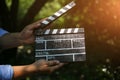 Cool hipster guy is holding in his hands a black clapperboard . Man is directing and filming some amateur cinema movie