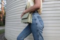 Cool hipster woman in fashion blue classic jeans with a leather handbag walks on the street, close-up Royalty Free Stock Photo