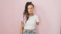 Cool hispanic amputee woman, standing over pink isolated background, seriously expressing relaxed lifestyle with armless tattooed
