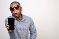 Cool Hispanic man holds a mobile phone with a blank screen on a white background