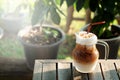 Cool ice caramel macchiato coffee on rough wooden table in topical garden. Royalty Free Stock Photo