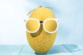 Cool image of melon with sunglasses on blue wooden table - summertime concept