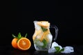 Cool lemonade made from oranges and mint in a glass jug. Ice cubes in the drink. Photo on a black background. Copy of the space Royalty Free Stock Photo