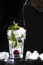 Cool lemonade is poured from a vintage vessel into a glass with cherries and ice. Mint leaves in a glass. Seasonal summer drink. Royalty Free Stock Photo