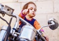 Cool little biker girl playing and having fun on fashioned motorcycle. Humorous portrait of child points to the road with finger Royalty Free Stock Photo