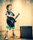 Cool little boy posing with electric guitar.