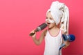 Cool little girl with hair dryer in hands. Portrait of beautiful female child singing with hair comb in hand isoalted on rosy