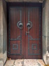 Cool looking ancient old closed wooden door in reddish color with metal ornaments and retro style handle Royalty Free Stock Photo