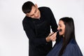 Cool male make-up artist doing makeup to young businesswoman. Beauty, fashion and gender stereotypes on white Royalty Free Stock Photo