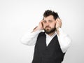 Cool man with black beard and white shirt is posing with headphones and smartphone in front of white background Royalty Free Stock Photo