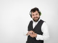 Cool man with black beard and white shirt is posing with headphones and smartphone in front of white background Royalty Free Stock Photo