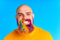 cool man with colorful beard looking at camera and feeling great mood in studio blue background