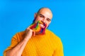 cool man with colorful beard looking at camera and feeling great mood in studio blue background