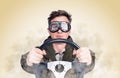 Cool man in stylish goggles with steering wheel, smoke around, yellow background. Front view. Car driver concept Royalty Free Stock Photo