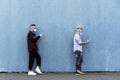 Cool men in a line using mobile phones while keeping social distance and wearing face medical mask - Friends watching video and