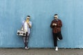 Cool men looking at mobile phone lean against blue wall - Couple of influencer guys listening music with vintage boombox stereo Royalty Free Stock Photo