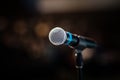 Cool mic on a stand in front of the concert hall, beautiful blurred dark background with a copy space for a message.