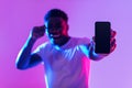 Cool mobile offer. Handsome African American guy demonstrating smartphone with blank screen in neon light