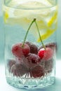 Cool non-alcoholic drink with lemon lobules and cherries in air bubbles in a glass decoration