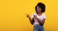 Cool offer. Cheerful african american lady pointing two fingers aside at copy space on yellow background, panorama Royalty Free Stock Photo