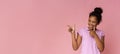 Cheerful black teen pointing at free space on pink background