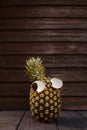 Cool pineapple with sunglasses on and dark wooden background