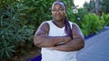 Cool plus-size african american woman, with braids, standing in the calming green park sunlight, arms crossed in serious Royalty Free Stock Photo