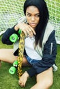 Cool pretty smiling afro-american happy young woman with skate board hanging aroung at foothball field Royalty Free Stock Photo