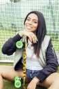 Cool pretty smiling afro-american happy young woman with skate board hanging aroung at foothball field Royalty Free Stock Photo