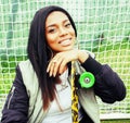 Cool pretty smiling afro-american happy young woman with skate board hanging aroung at foothball field, lifestyle people Royalty Free Stock Photo