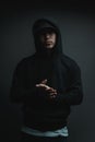 Cool rapper with black hoodie and cap clapping his hands in front of grey background Royalty Free Stock Photo