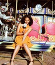 Cool real teenage girl with candy near carousels at amusement park walking, having fun Royalty Free Stock Photo