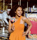 Cool real teenage girl with candy near carousels at amusement park walking, having fun Royalty Free Stock Photo