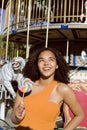 Cool real teenage girl with candy near carousels at amusement park walking, having fun Royalty Free Stock Photo