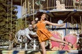 Cool real teenage girl with candy near carousels at amusement park walking, having fun Royalty Free Stock Photo