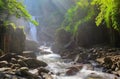 A cool refreshing waterfall in a mysterious forest with sunlight shining through the lavish greenery