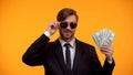 Cool rich man in sunglasses showing bunch of dollars, lottery winner, wellness Royalty Free Stock Photo