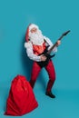 Cool Santa Claus rock musician plays on electric guitar on color background. New Year party. Royalty Free Stock Photo