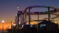 Tourists enjoy a rollercoaster ride in Santa Monica amusement park at sunset