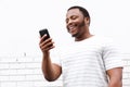 Cool smiling young black man looking at mobile phone