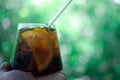 Cool soft drink with orange slices inside glass on hand