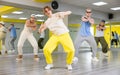 Cool talented teens in casual wear exercising modern dance moves in training room