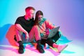 Cool team young girl and guy working on laptop creating design project. Colored neon studio light Royalty Free Stock Photo