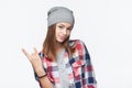 Cool teen girl wearing checkered shirt and beanie hat gesturing rock sign