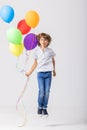 Teenage boy holding a bunch of balloons jumps in an empty room Royalty Free Stock Photo