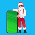 Cool trendy Santa Claus in sunglasses points to a big phone. Santa in a white shirt with suspenders rests his hand on a huge