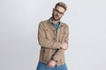 Cool unshaved fashion guy in jacket holding arms in fashion pose