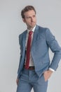 Cool unshaved man in blue suit holding hand in pocket and looking to side Royalty Free Stock Photo