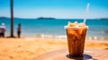 Iced coffee sits enticingly on a cafe table with a beach backdrop Royalty Free Stock Photo